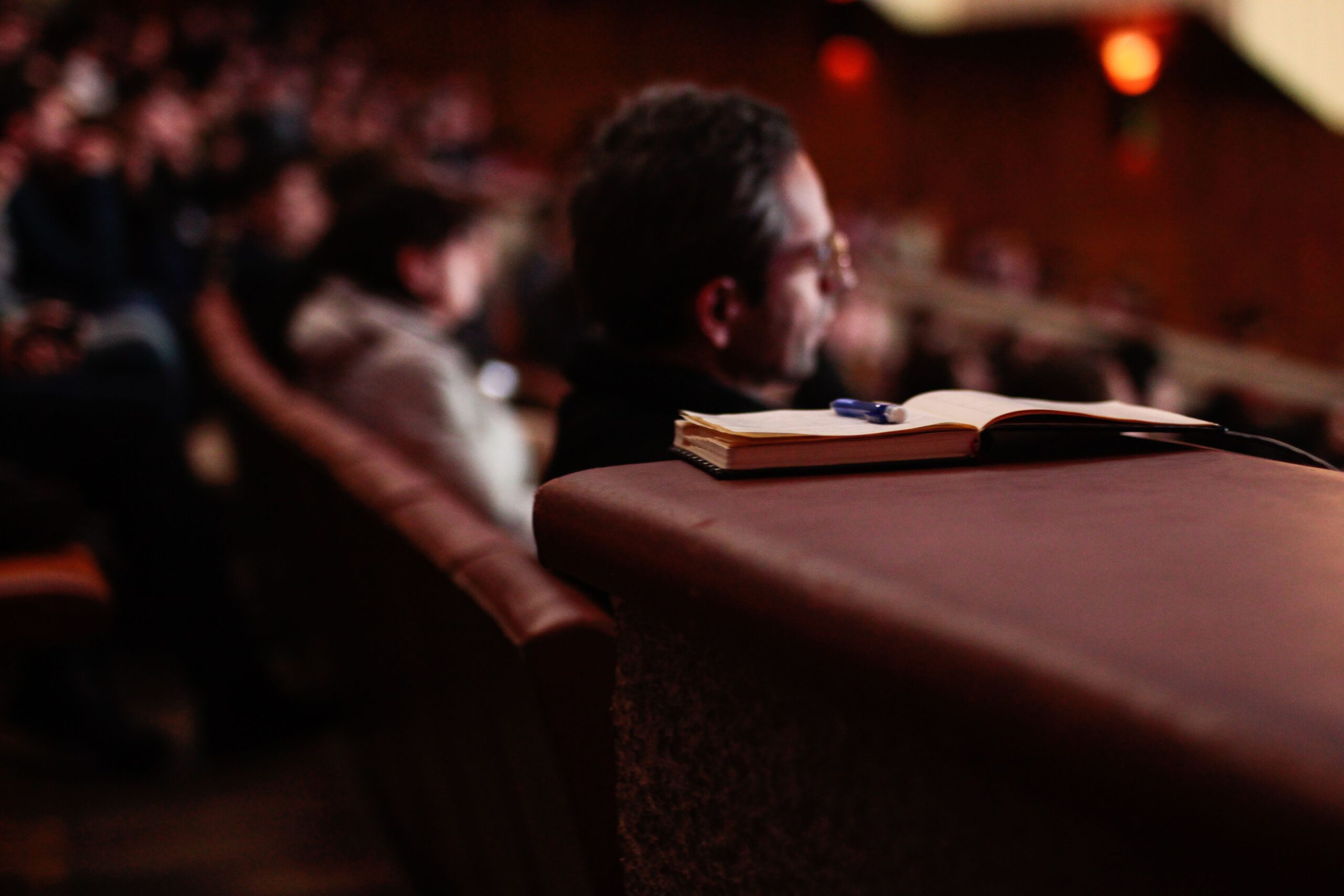 Photograph of a open notepad in a lecture hall with people in the background